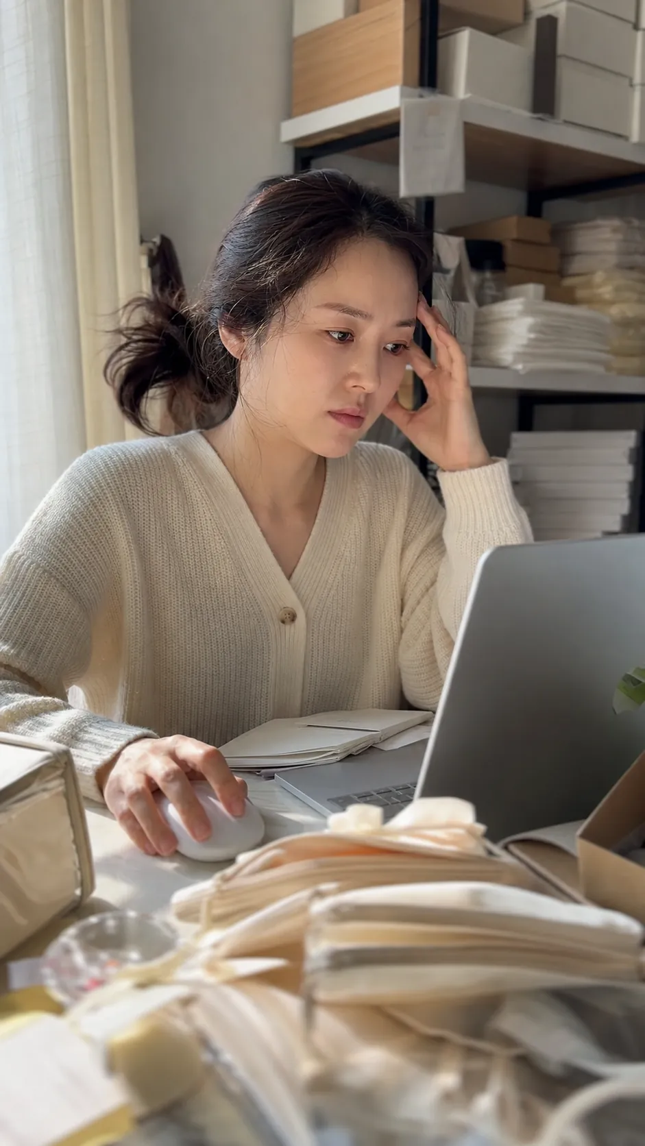 1인 브랜드 온라인 판매, 직접 할까 맡길까 — 진짜 질문은 경계선입니다 | OSC 1 30대 초반 한국인 여성 1인 브랜드 대표가 포장 박스에 둘러싸인 홈오피스에서 노트북을 보며 고민하는 모습